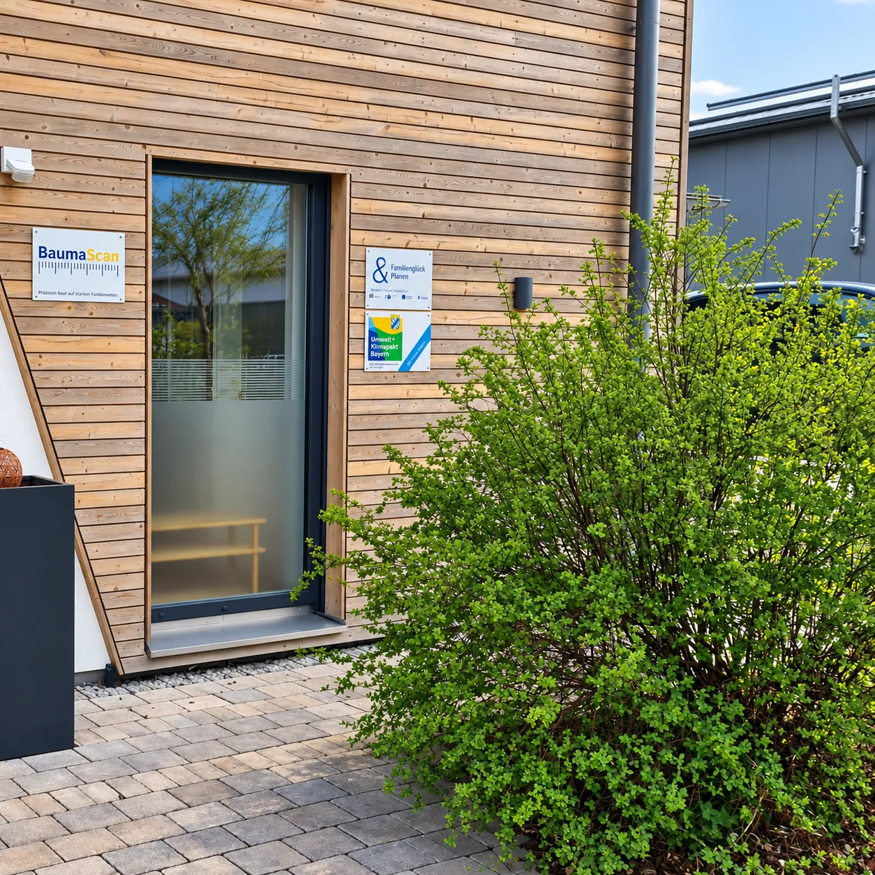 Entrance with BaumaScan company sign, wooden facade and green area